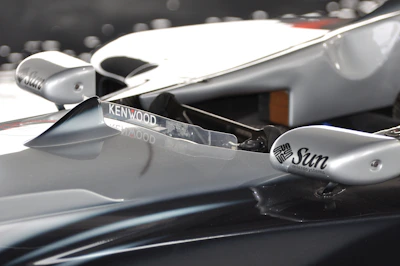 Close-up of a race car sponsor logos shining under the sunlight on a racetrack.