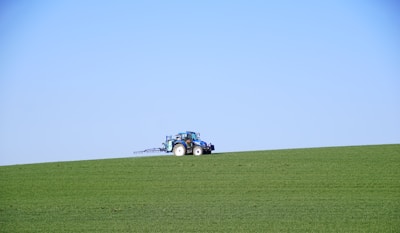 A tractor tilling rich soil under a bright blue sky on a peaceful farm.