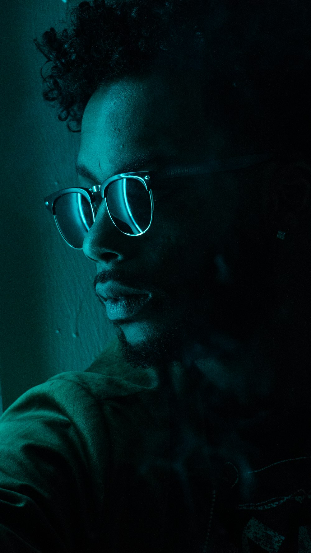 man sitting near wall wearing black framed sunglasses