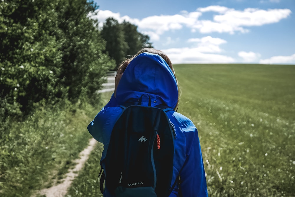 person wearing blue hooded jacket on grass field