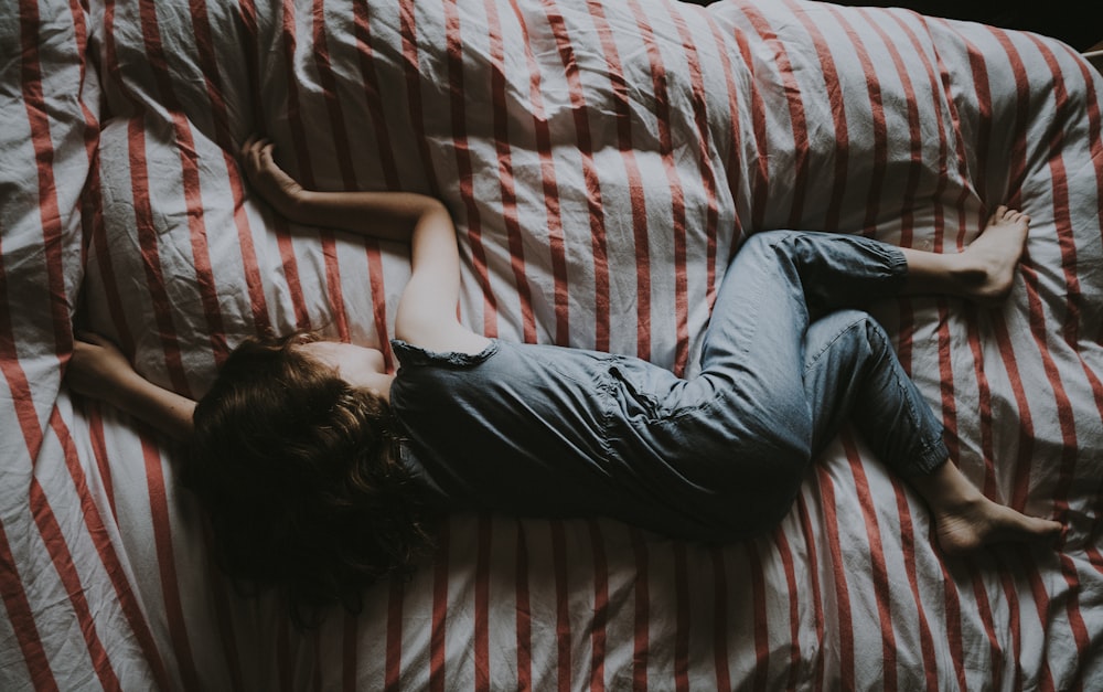 kid sleeping on red and gray bed