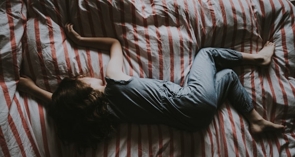 kid sleeping on red and gray bed