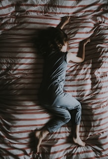 woman lying on gray and red striped textile