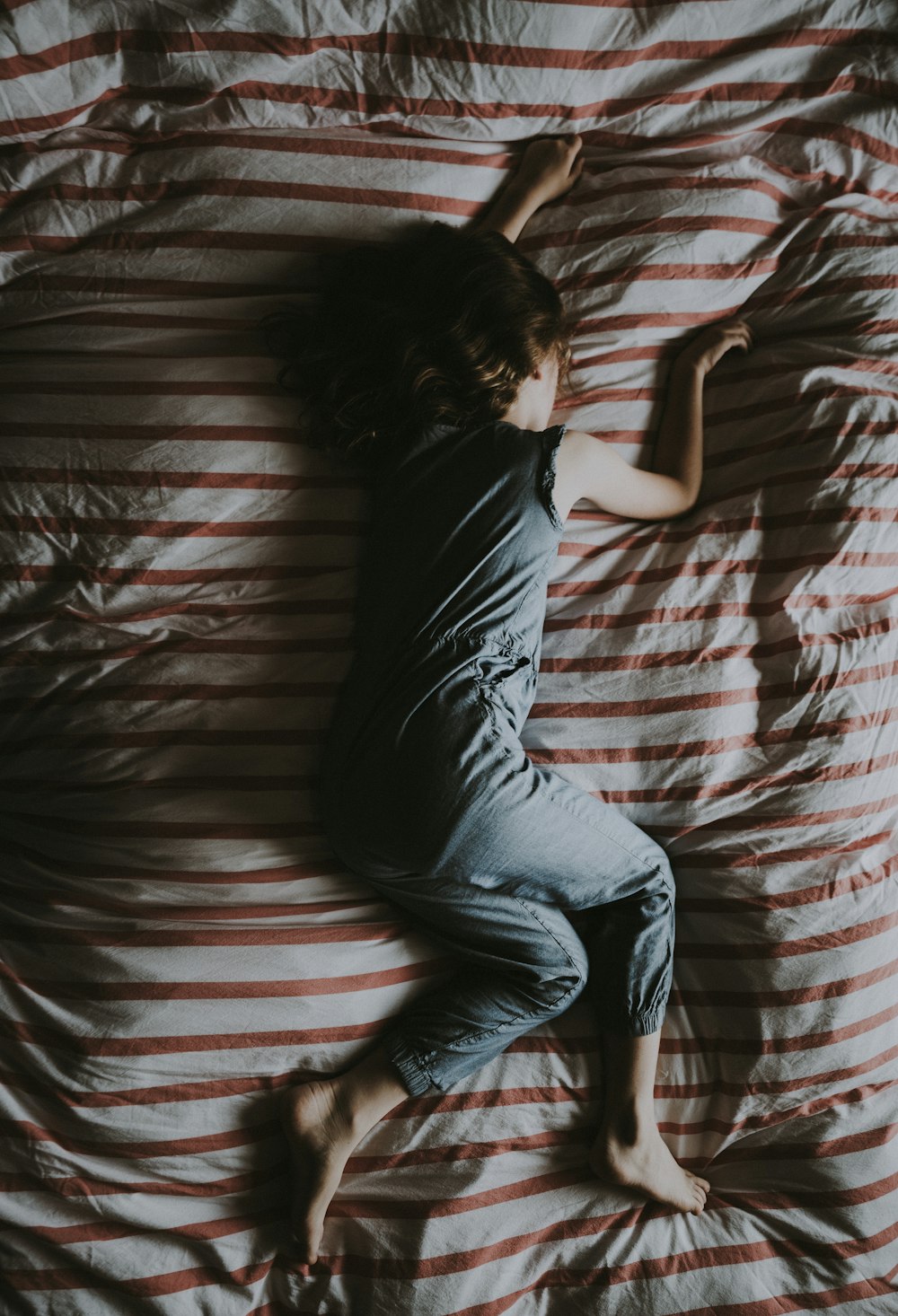 woman lying on gray and red striped textile