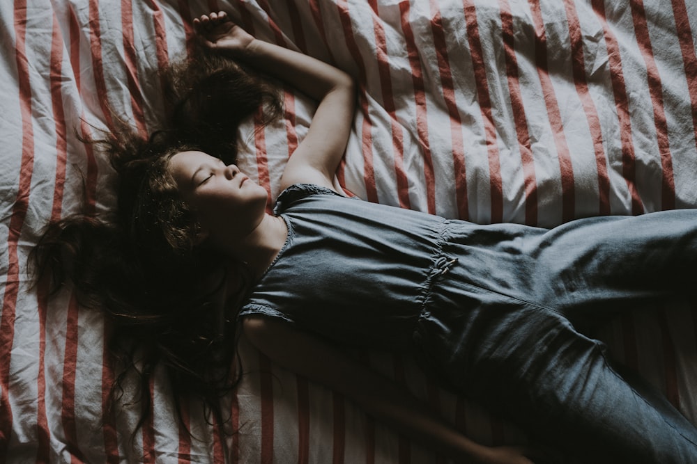 a woman laying on top of a bed next to a red and white blanket