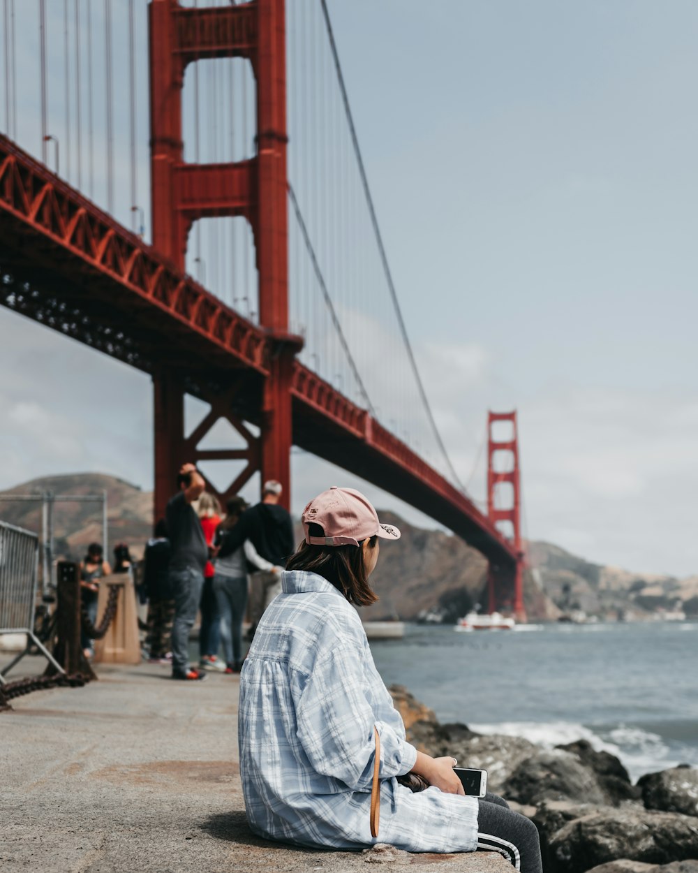 donna seduta sul pavimento di cemento vicino al Golden Gate Bridge,