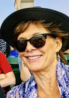 A stylish woman showcasing earrings at an outdoor café, enjoying a sunny day.