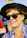 Smiling woman wearing a stylish hat and glasses in outdoor sunlight