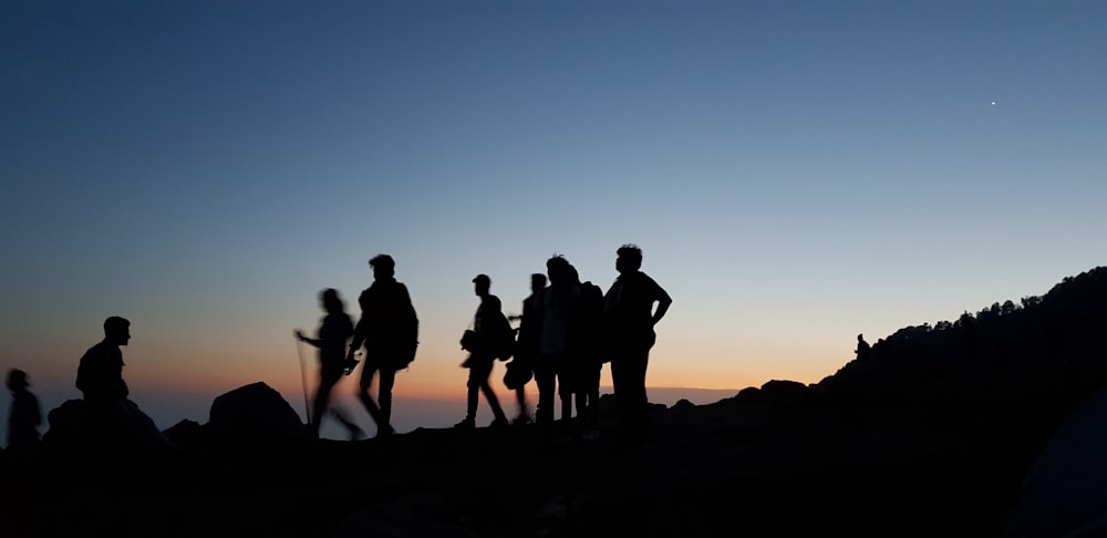 Silhouette auf Menschen, die während der blauen Stunde auf dem Berg stehen