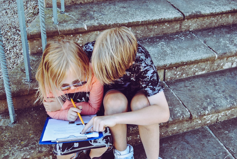 Niño y niña respondiendo preguntas en papel blanco