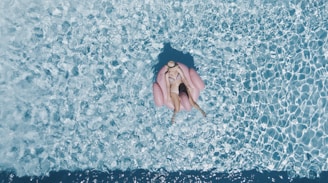 woman on pink buoy surrounded by body of water during daytime