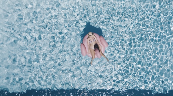 woman on pink buoy surrounded by body of water during daytime