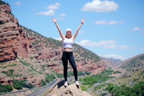 woman wearing white top and black pants standing on cliff