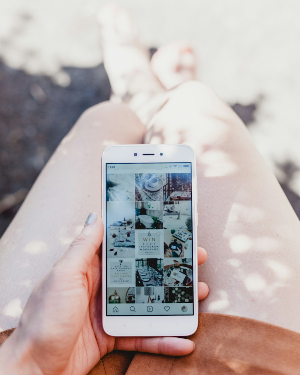 persona che tiene in mano uno smartphone bianco che mostra il feed di Instagram