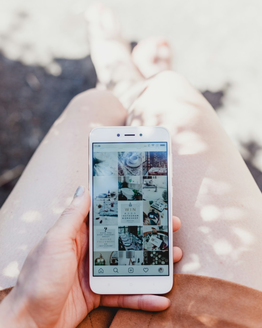 personne tenant un smartphone blanc montrant le flux Instagram