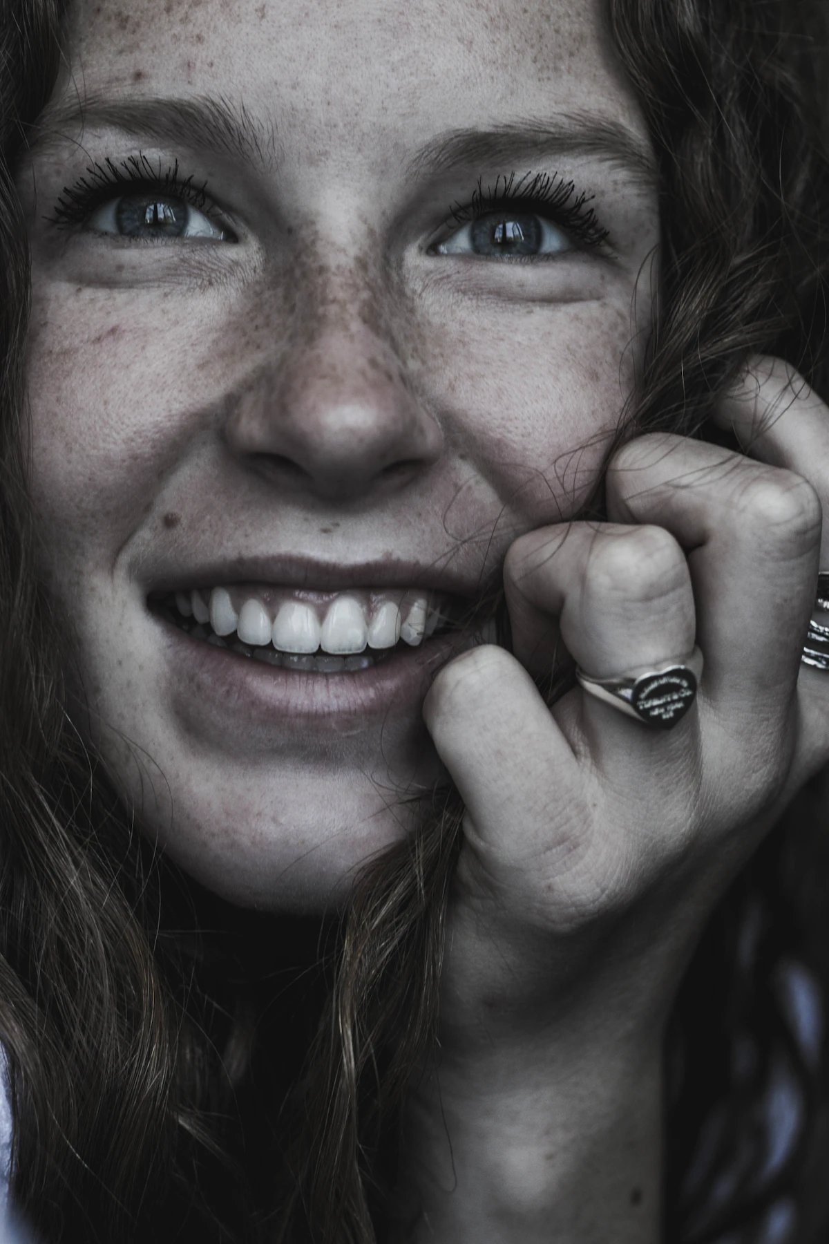Close-up portrait of a smiling woman with visible natural freckles across her cheeks and nose in warm natural light
