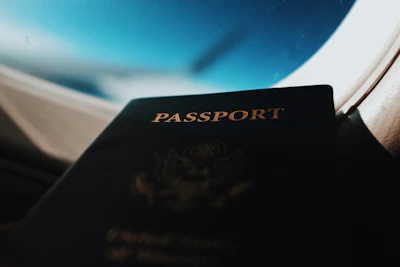 A close-up of hands holding a passport and boarding pass with a blurred airplane in the background