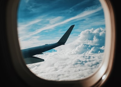 person taking picture of plane wings while flying during daytime voyage teams background