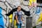 A confident young person wearing edgy Youngka apparel, standing against a graffiti-covered urban wall.