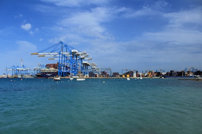 Cargo being loaded onto a ship with cranes at a bustling Saudi port under clear blue skies.