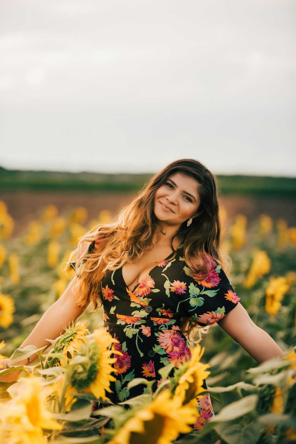 woman standing in sunflower field while smiling during daytime
