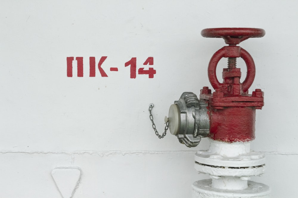 Roter und weißer Hydrant neben weißer Wand