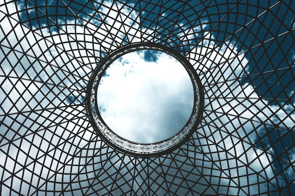 a circular mirror reflecting the sky in a metal structure