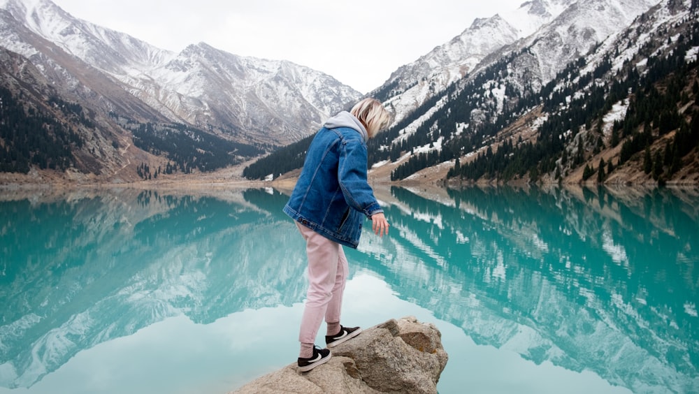 Mujer de pie en la roca frente al lago