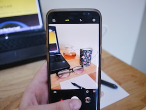 Lifestyle shot of a woman’s desk featuring a modern phone case, a pastel notebook, and a warm cup of tea.
