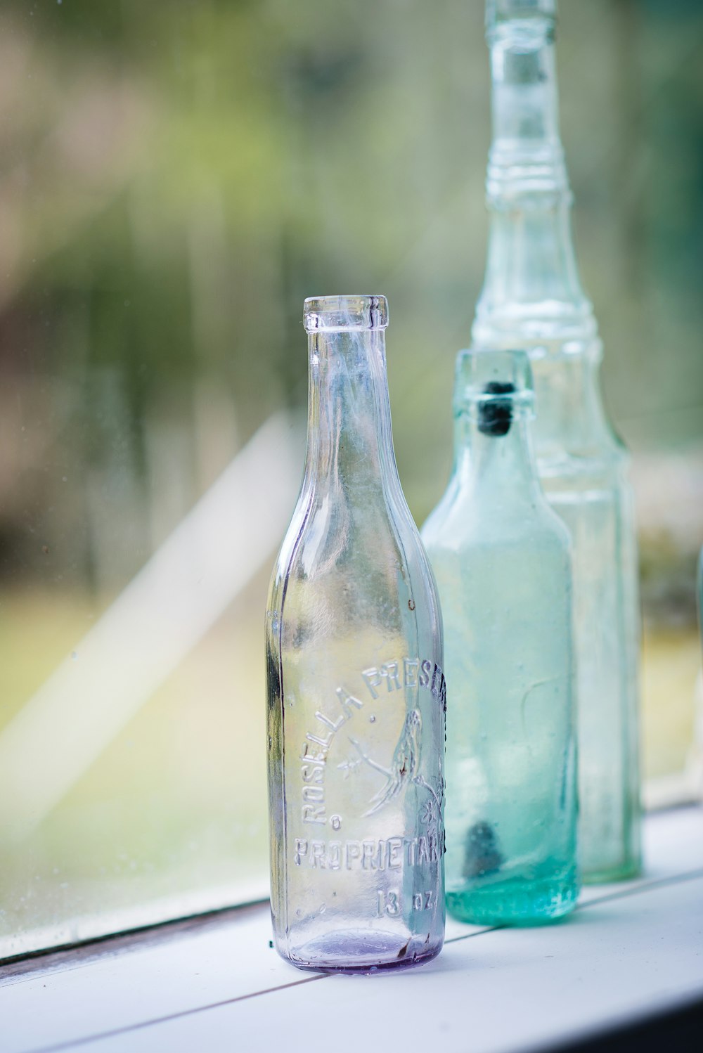 Photo sélective de trois bouteilles en verre transparent