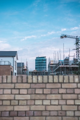 View of a construction site with scaffolding and brick walls rising under a clear blue sky.