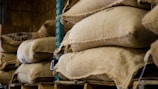 Stacks of cocoa bean sacks ready for shipment at a bustling Ghanaian warehouse.