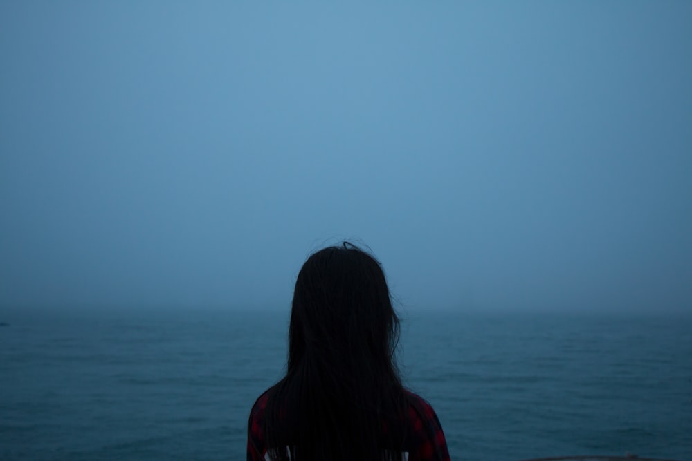 photo of silhouette woman facing body of water