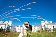Bride and groom sharing a joyful moment in front of a medieval castle.