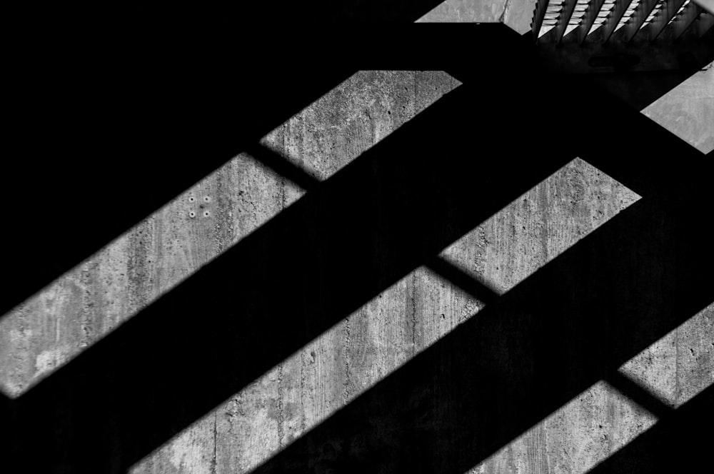 a black and white photo of a bench in the shadows