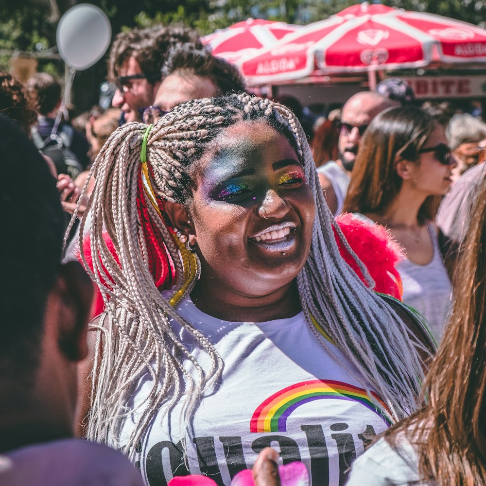 smiling woman wearing shirt standing in middle of crowd