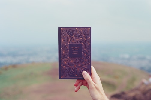 Close-up of a child’s hands holding a book with textured earthy cover.