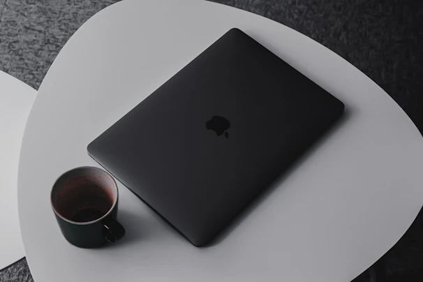 A modern laptop bag placed beside a laptop and coffee cup on a clean white table.