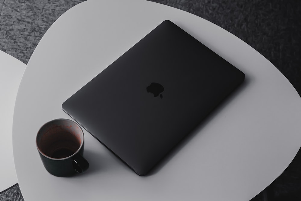 MacBook Pro neben Tasse auf dem Tisch