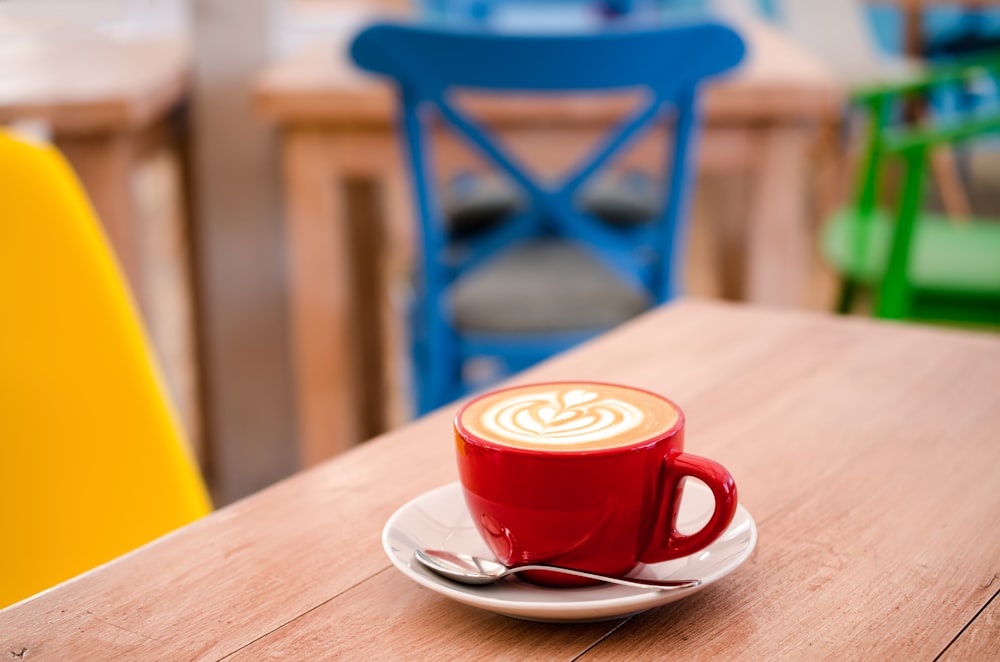 Caneca de café expresso vermelho com molho branco em cima da mesa de madeira