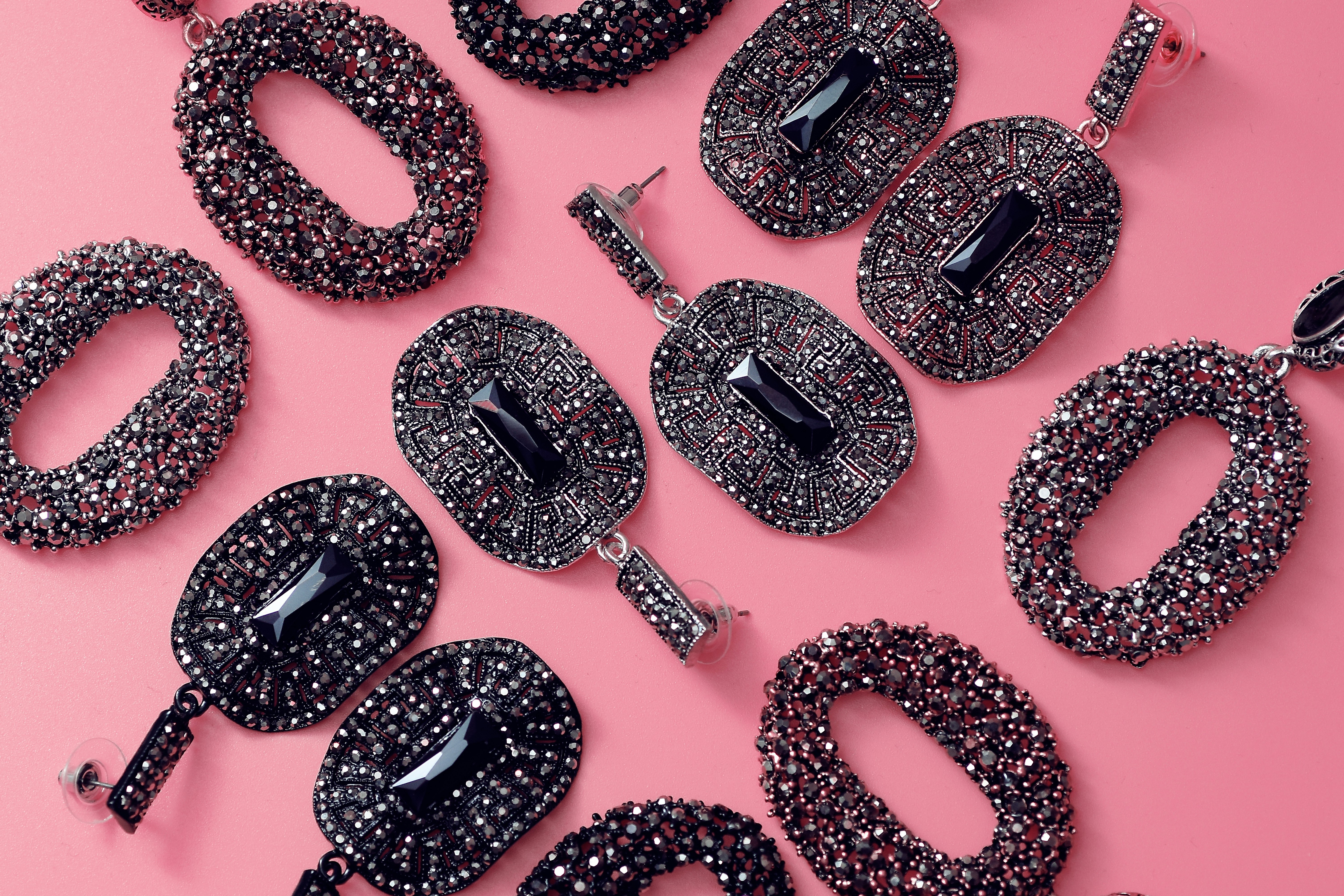 black gemstone pendants on pink surface