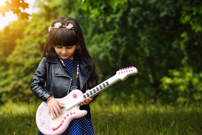 A confident young woman striking a pose with her electric bass guitar outdoors.
