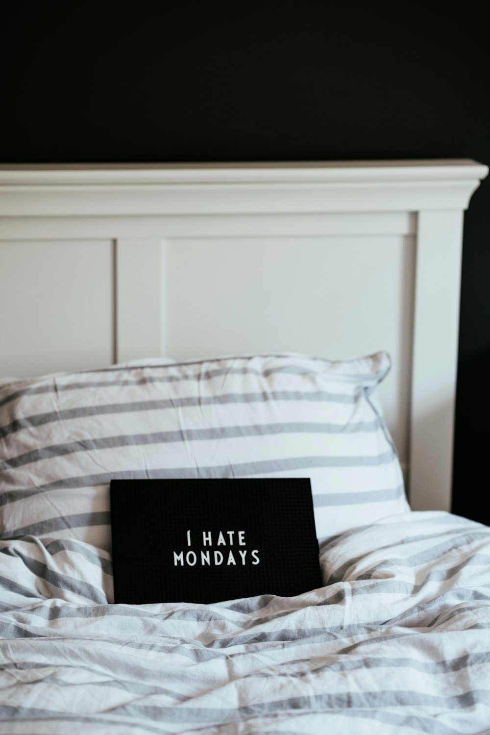 rechteckiges schwarzes Ich hasse Montags-bedrucktes Brett auf dem Bett