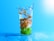 A close-up of a glass filled with clear alkaline water, surrounded by fresh fruits.