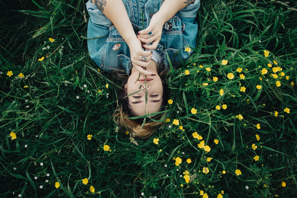 woman lying on grass ground with yellow petaled flowers