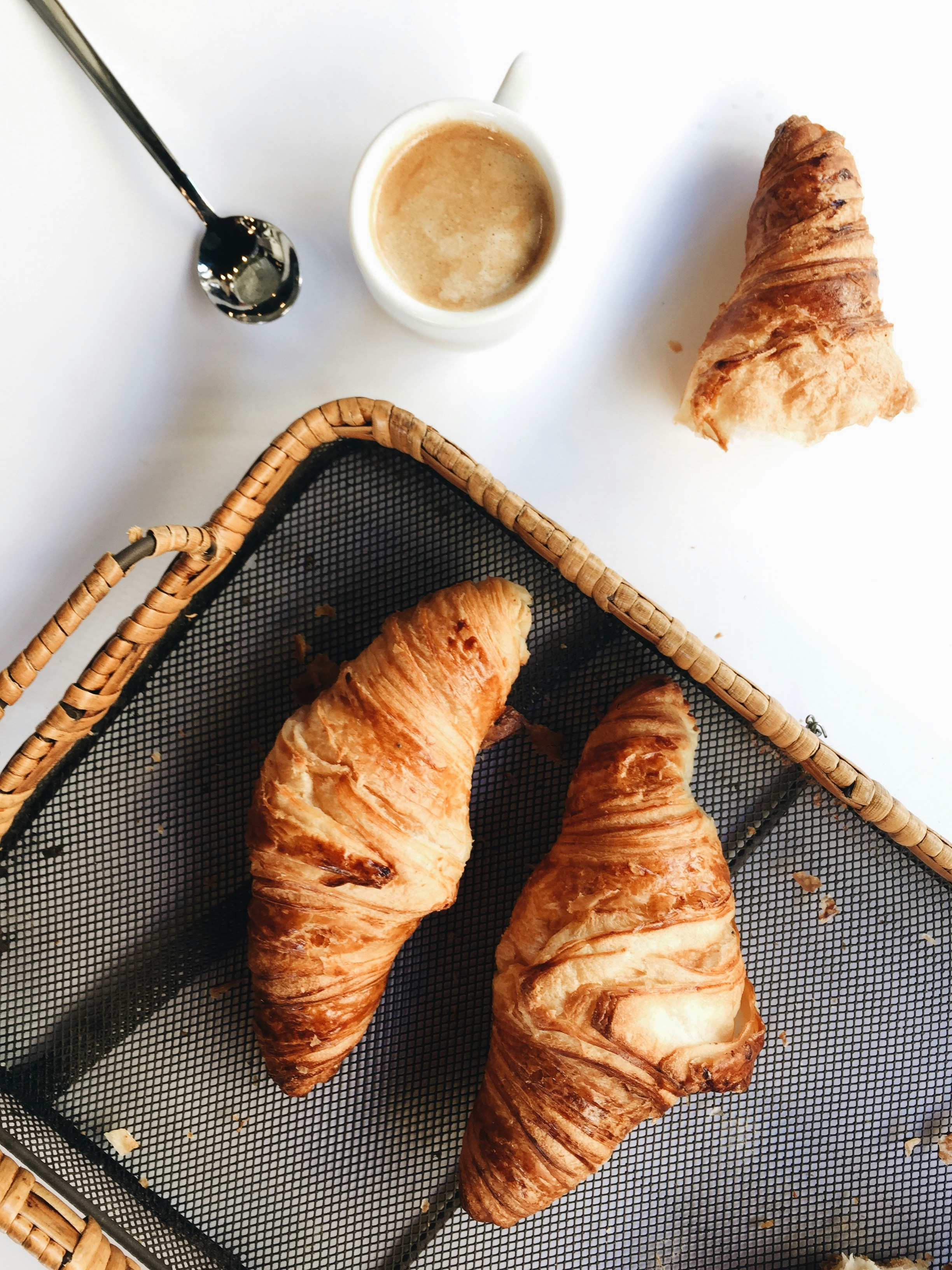 Assorted fresh croissants and pastries in wicker bread basket on white background