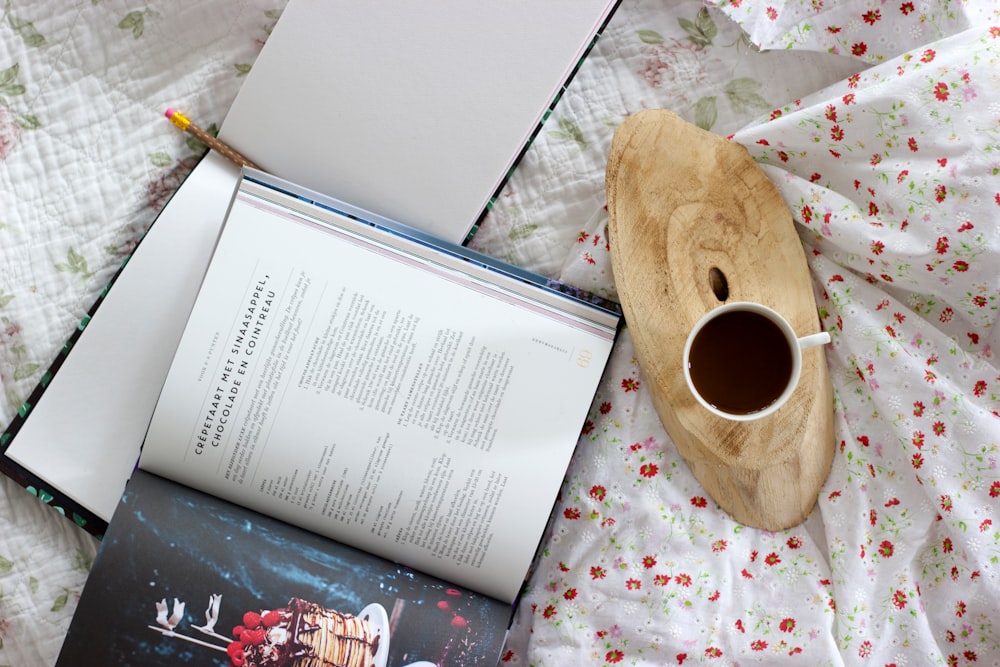 white ceramic mug beside opened book