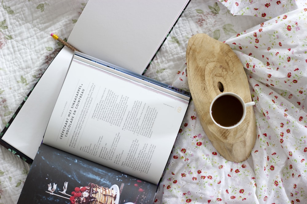 Tasse en céramique blanche à côté d’un livre ouvert