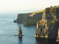 rock formation beside sea under white sky