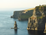 rock formation beside sea under white sky